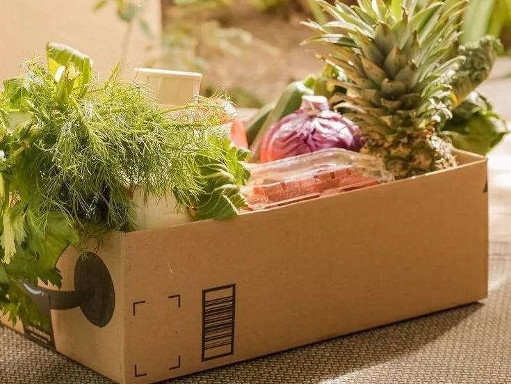 Ein offener Karton mit Lebensmitteln - Kräuter, Gemüse und Obst