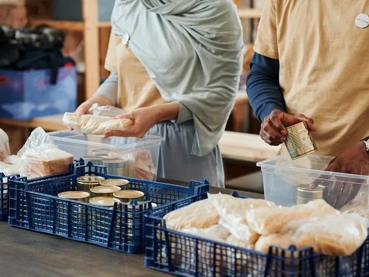 Zwei Personen stellen aus offenen Lebensmittelkörben Kisten zusammen