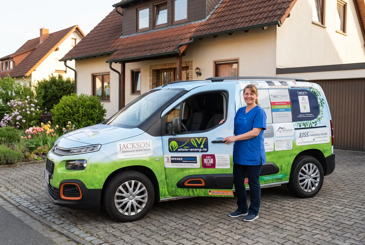 Eine Pflegekraft eines ambulanten Hospizdienstes steigt vor einem Wohnhaus aus einem beschrifteten Fahrzeug, freundliche und ruhige Stimmung.