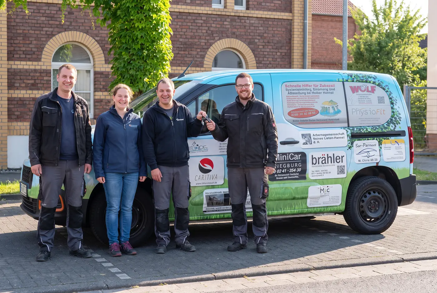 Team der INKLUPLAY gGmbH vor dem neuen Toyota Proace bei der Fahrzeugübergabe in Schmallenberg, mehrere Menschen lachen und stehen beisammen.